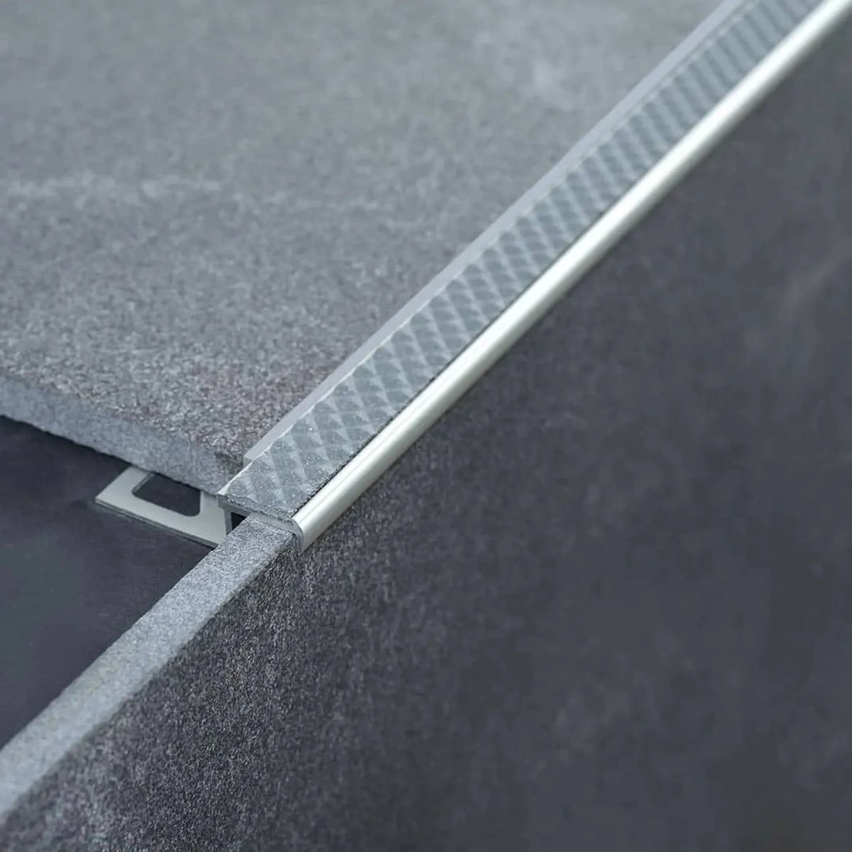Zamontowany profil krawędziowy schodowy z aluminium antypoślizgowy ze stalowoszarą wkładką na stopniu z szarymi płytkami #A0001725 #A0001736