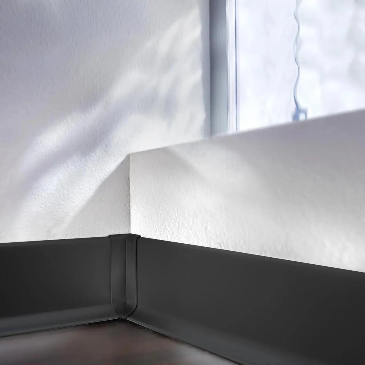 An einer Wand verbaute Sockelleiste mit Fokus auf die schwarz Innenecke Sockelleiste Aluminium #A0005091
#A0005096