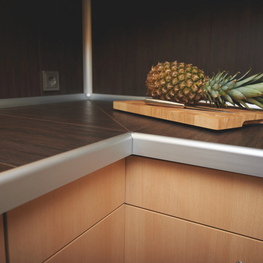 Ambientebild silbernes Arbeitsplattenprofil mit Innenecke installiert auf einer Arbeitsplatte auf der eine Ananas liegt #A0002417 #A0002401 #A0002385