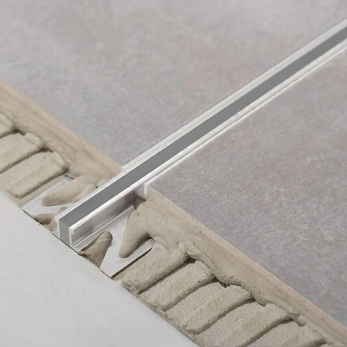 Profilé de joint de dilatation Dural en aluminium avec garniture EPDM grise appliquée entre 2 carreaux