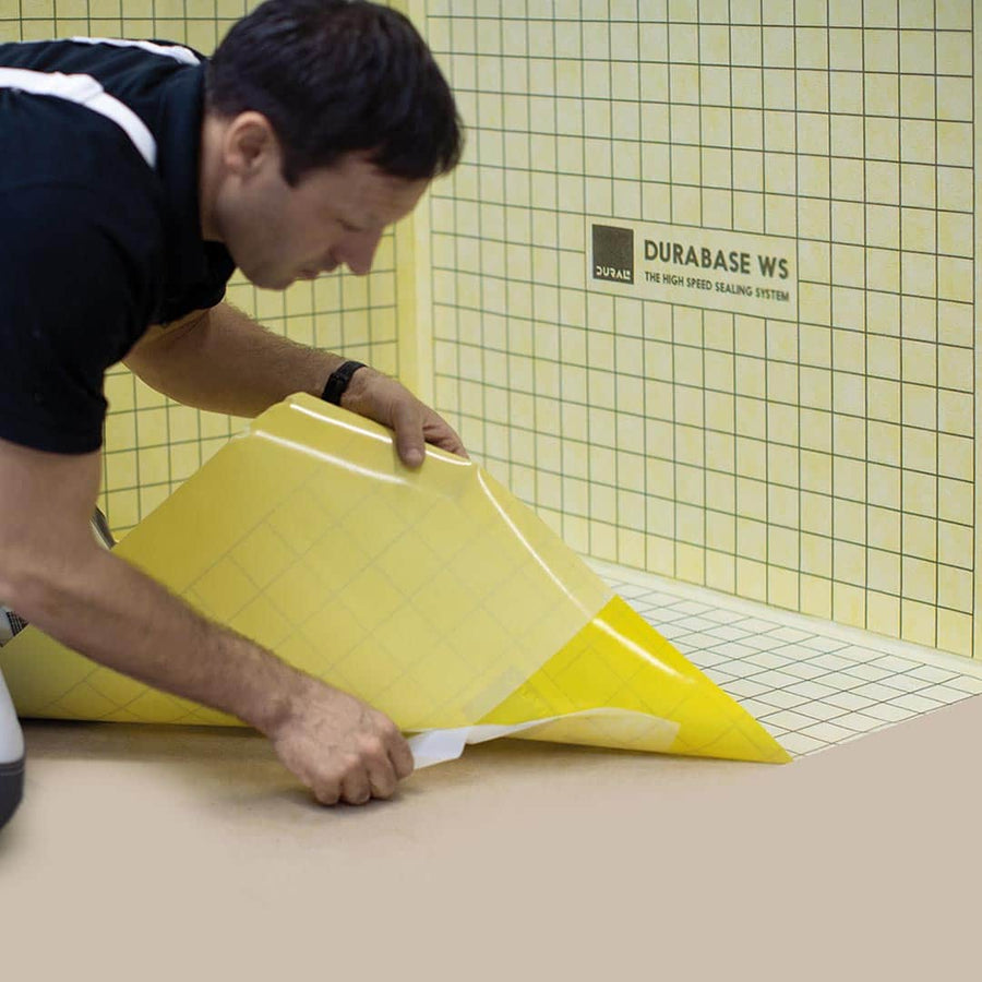 Le carreleur pose la membrane d'étanchéité jaune Durabase WS