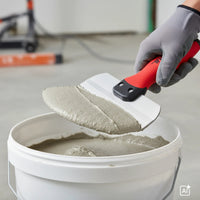 Filler compound is being scooped from a bucket with the stainless steel bucket spatula
