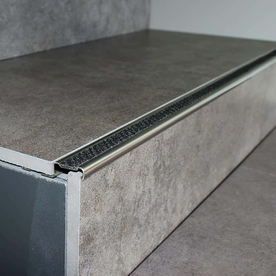 Verbautes Treppenkantenprofil Aluminium rutschhemmend mit nachtscwarzer Einlage an Stufe mit grauen Fliesen #farbe_nachtschwarz