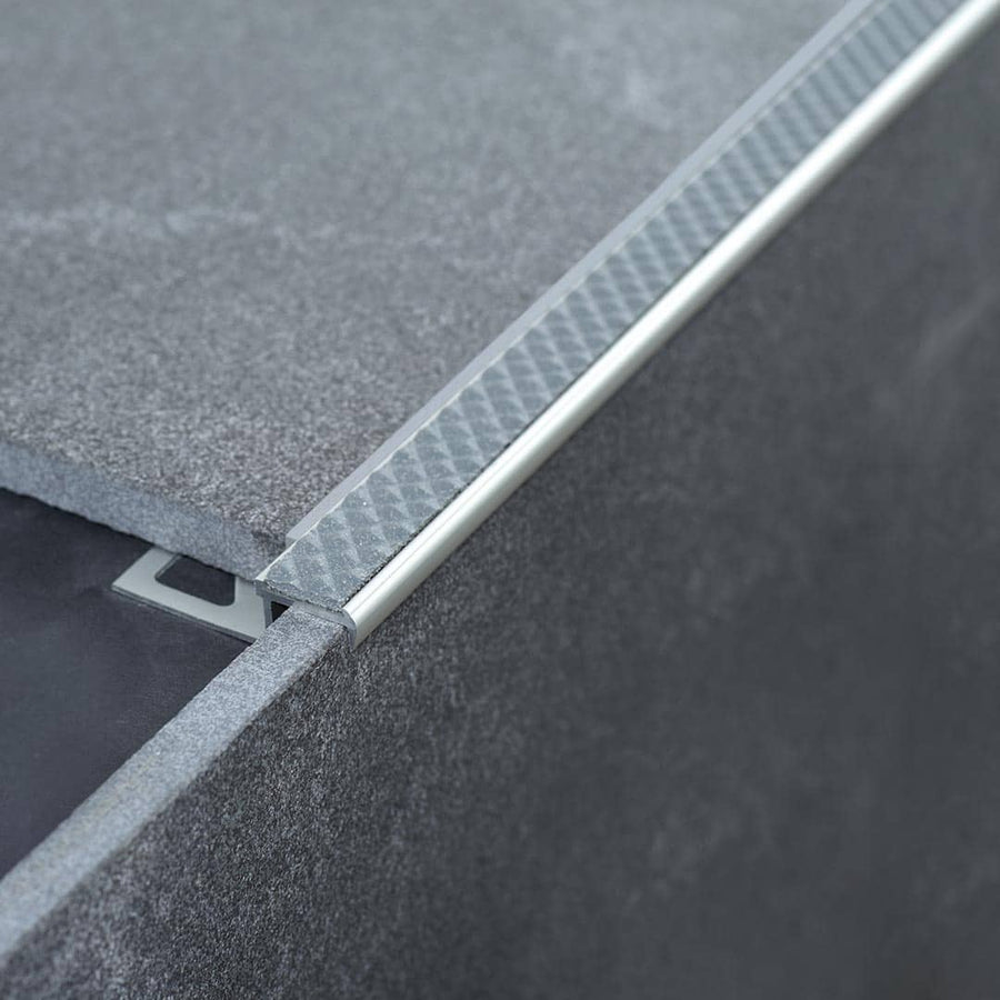 Verbautes Treppenkantenprofil Aluminium rutschhemmend mit stahlgrauer Einlage an Stufe mit grauen Fliesen #farbe_stahlgrau
