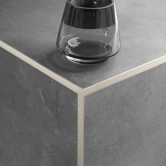 Sandfarben pulverbeschichtetes Winkelprofil aus Aluminium mit schmaler Sichtkante und matter Optik verarbeitet an der Außenecke unter dunklem Fliesenbelag.