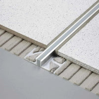 DURAL expansion joint profile made of stainless steel installed under white tiles. Part of the profile is exposed in the adhesive bed