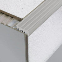 Stair profile with wide rubber insert in grey installed under tile. Part of the punched leg is exposed in the adhesive bed #A0001753 #A0001757